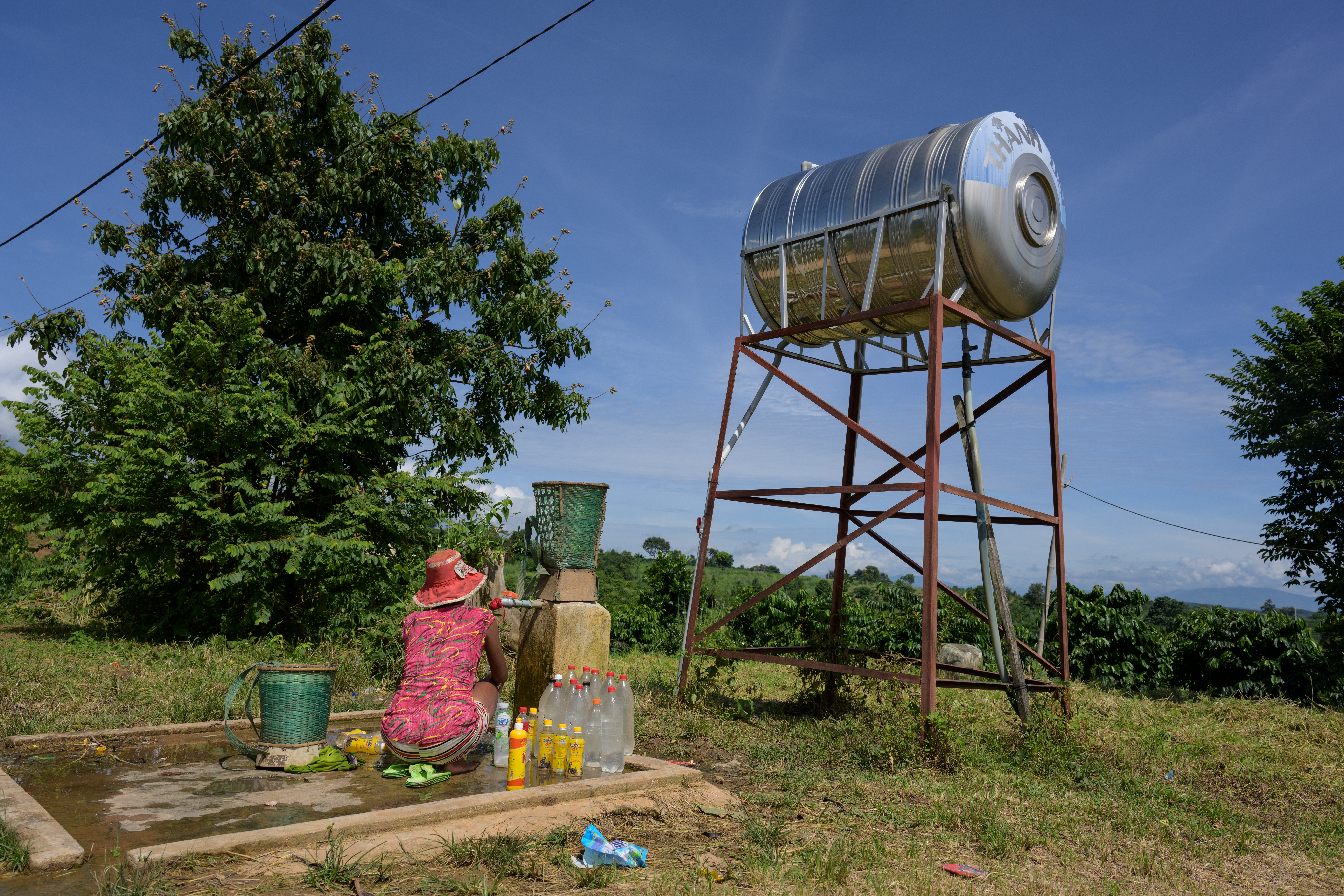 woman filing water bottles with clean water from new water tank.