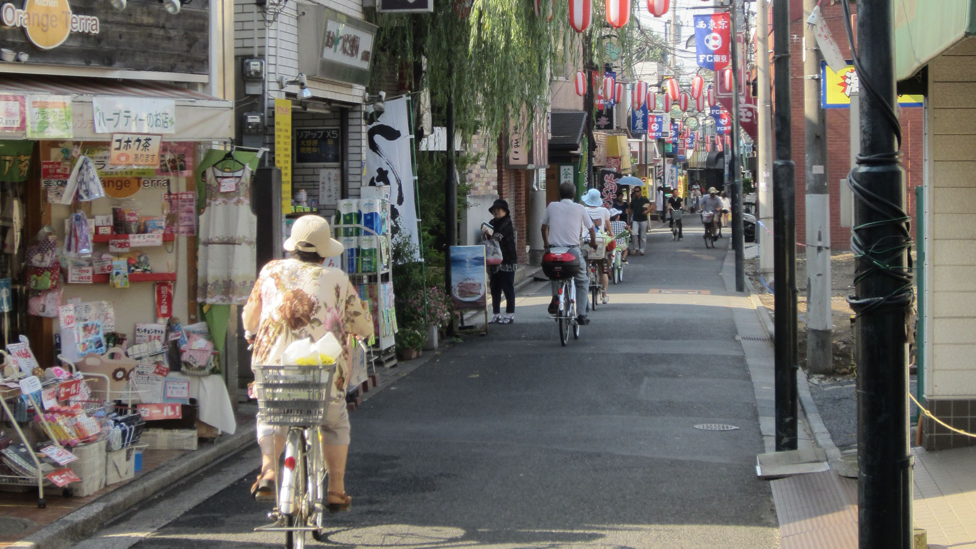 People riding bikes down a street in an Asian city